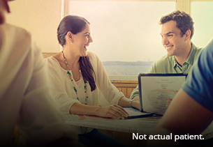 Lady and man smiling at each other with another person working on an open laptop opposite them